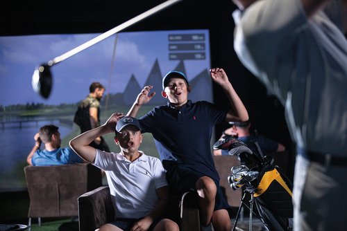 A golfer celebrating a successful swing in an indoor golf facility, symbolizing the journey of unveiling secret triumphs through practice and perseverance.